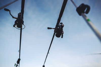 Low angle view of fishing rod spools against sky
