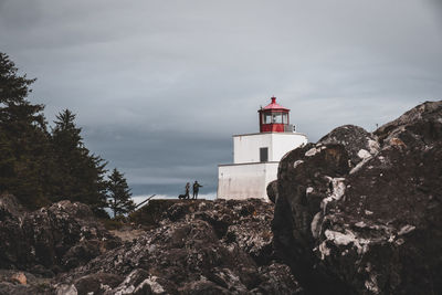 Low angle view of lighthouse by buildings against sky