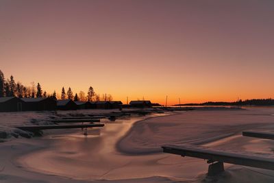 Snow covered landscape against clear sky during sunset