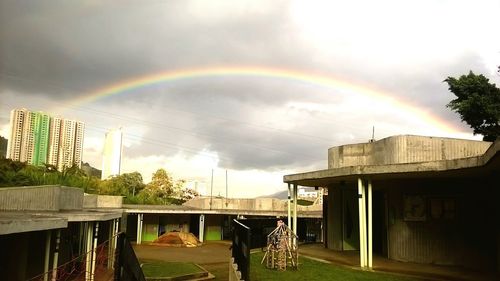 Rainbow over city against sky