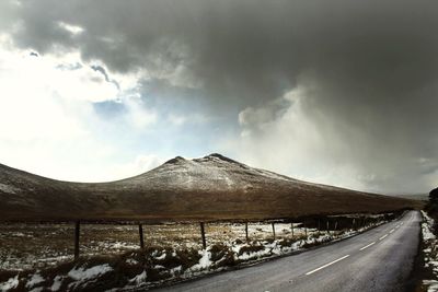 Snow covered landscape against cloudy sky