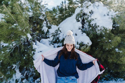 Woman wearing warm clothing against trees during winter