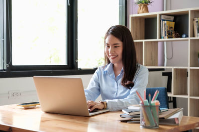 Young woman using phone while sitting on table
