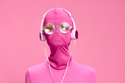 Portrait of woman wearing mask against pink background