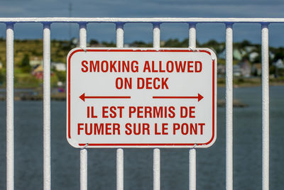 A metal sign expressly permitting smoking in english and french attached to a railing or fence
