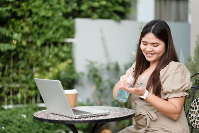 Young woman using mobile phone while sitting on table