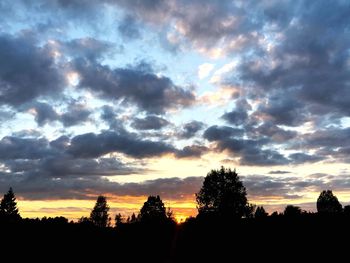 Silhouette trees against dramatic sky during sunset