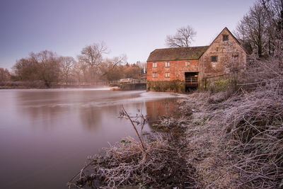 Abandoned building by lake against sky