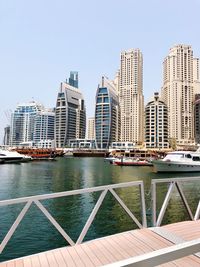 View of modern buildings by river against clear sky