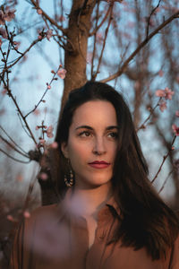 Portrait of young woman against tree