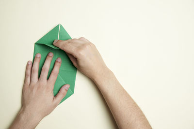 Midsection of person holding paper against white background