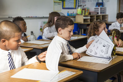 Students looking at books during lesson in classroom