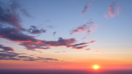 Low angle view of birds flying against sky during sunset