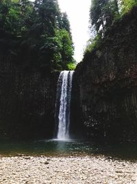 Scenic view of waterfall in forest against sky