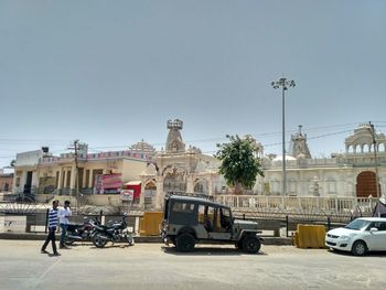 Cars on road against sky in city