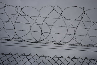 Low angle view of barbed wire against sky