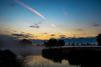 Scenic view of silhouette trees against cloudy sky