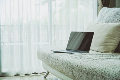 Close-up of laptop on bed at home