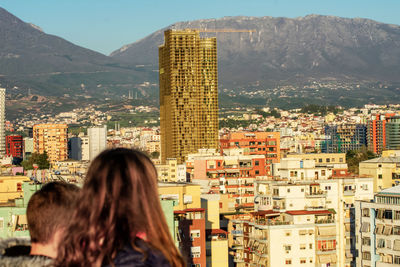 Woman looking at city buildings against mountains