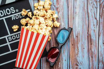 Popcorn with film slate and 3-d glasses on table