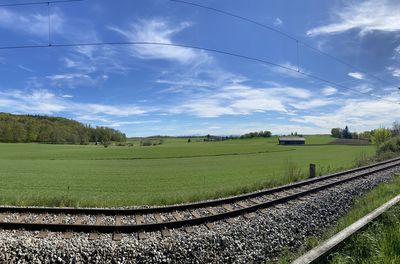 Railroad track amidst field against sky