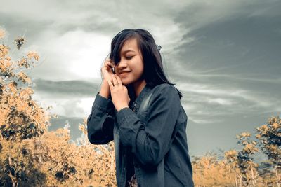 Young woman using mobile phone against sky