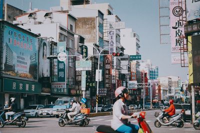 Men riding motor scooters on road in city