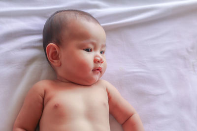 Portrait of cute baby girl lying on bed