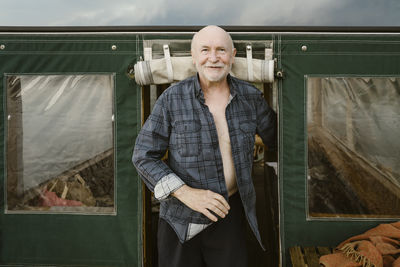 Portrait of senior man standing at houseboat entrance