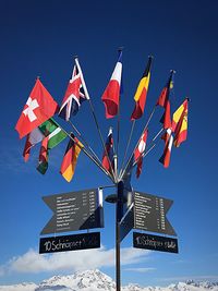 Low angle view of flags against blue sky