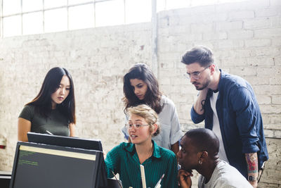 Young female entrepreneur having discussion over computer codes with hackers in office