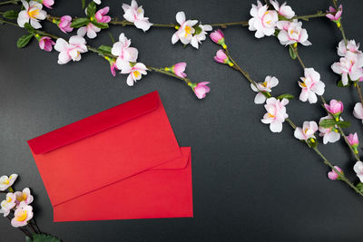 High angle view of red envelopes with flowers on table