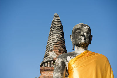 Low angle view of buddha statue at wat mahathat against clear sky