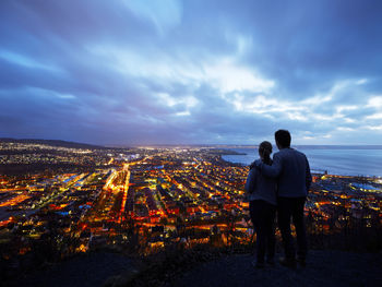 Couple looking at illuminated city at dusk