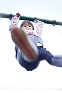 Low angle view of happy girl on swing