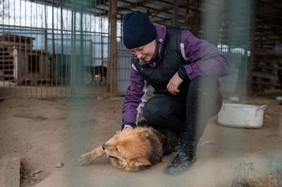 Volunteer in the nursery for dogs. woman volunteer in a cage with a stray dog at an animal shelter