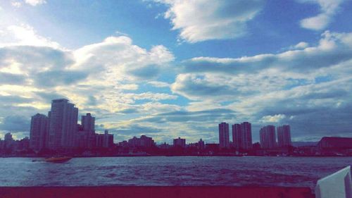 Skyscrapers in city against cloudy sky