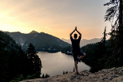 Man standing on mountain peak during sunset