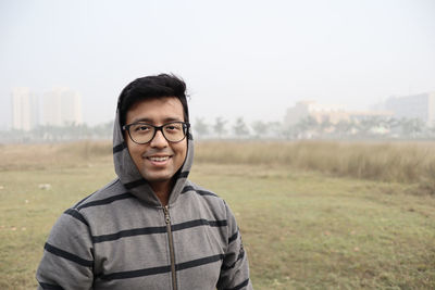 Portrait of smiling young man standing on field