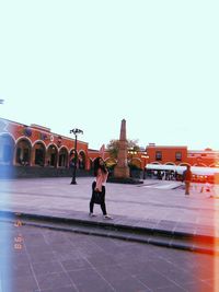 Man walking on city against clear sky