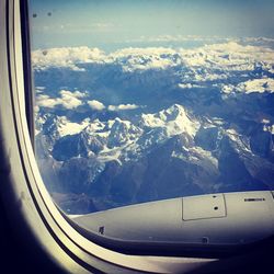 Aerial view of snowcapped mountains seen through airplane window