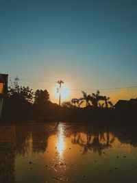 Silhouette plants by lake against sky during sunset