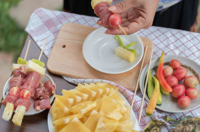 Cropped image of hand putting food in skewer