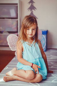 Portrait of cute girl wearing angel wings sitting at home