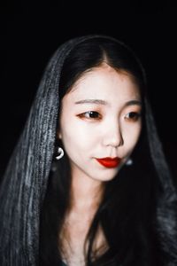 Close-up portrait of beautiful young woman over black background