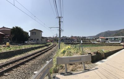 Railroad tracks by buildings against clear sky