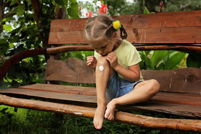 Cute girl with injured knee sitting on bench