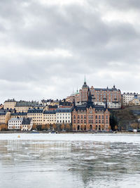 Buildings in stockholm by the frozen water against sky