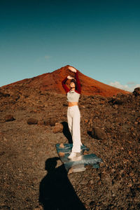 Woman standing on rock against clear sky