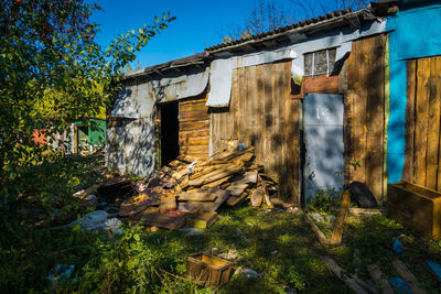 Old abandoned house by building against sky